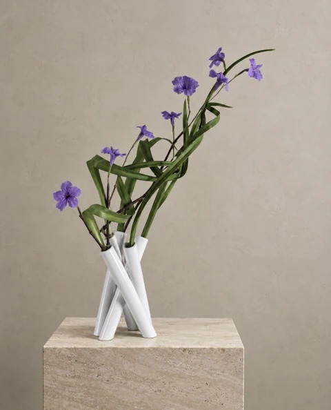 Floral study with small violet flowers and slender leaves in a white vase of entwined tubes